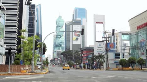 Large-and-empty-avenue-of-big-brands-and-companies-where-a-yellow-taxi-passes-by-and-a-person-crosses-the-street