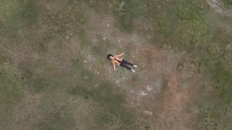 Aerial-drone-top-down-ascendent-circling-over-woman-lying-on-meadow
