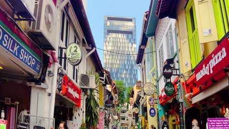 Bunte-Schilder-An-Den-Schaufenstern-Von-Cafés-In-Der-Haji-Lane-In-Singapur-Mit-Pan-Pacific-Hotel-Im-Hintergrund