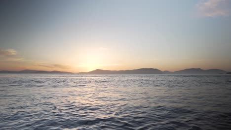 Majestätischer-Sonnenuntergang-über-Meereslandschaft-Und-Hügeln-Am-Horizont,-Schwenkansicht-Rechts