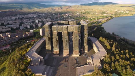 Aerial-reveal-of-Chronicle-of-Georgia-monument-at-sunset,-Tbilisi-hilltop