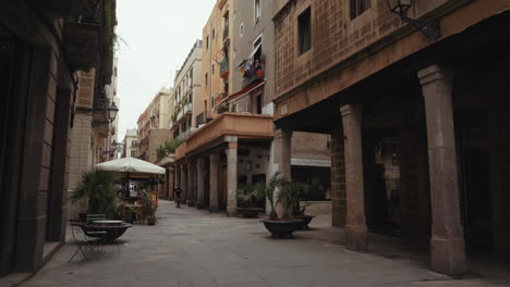 Barcelona---Carrer-del-Rec-empty-streets-and-balconies-on-pillars,-with-lone-skateboarder