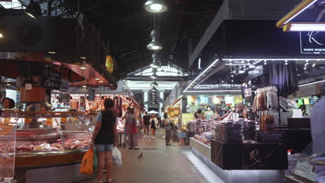 Barcelona---Mercado-de-La-Boqueria,-long-steady-tracking-shot-through-closed-market-with-stalls-and-shoppers,-Covid-19-Pandemic