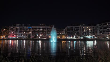 shot-from-the-meadow:-a-fountain-in-the-center-of-the-restaurants-at-night,-Montpellier---France