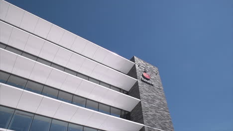 Bank-Logo-On-Building-Facade-Of-Rabobank-In-Gouda,-Zuid-Holland,-The-Netherlands-Against-Blue-Sky