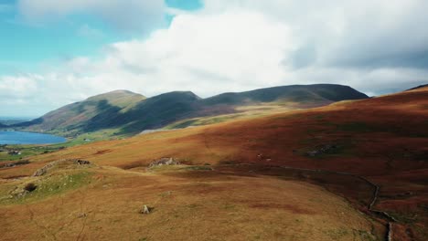 Luftdrehung-Rechts-Vom-See-Zu-Den-Mit-Orangefarbenem-Gras-Bedeckten-Hügeln-Zum-Snowdonia-Berg