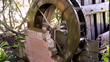 Small-garden-watermill-wheel-turning-in-a-small-stream-by-wooden-fence