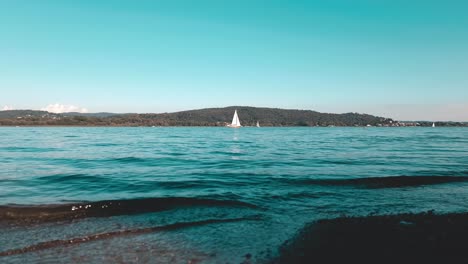 Filmische-Blaugrüne-Tiefwinkelansicht-Einer-Yachtkreuzfahrt-In-Ruhigen-Gewässern-Des-Offenen-Sees-Des-Lago-Maggiore-In-Italien