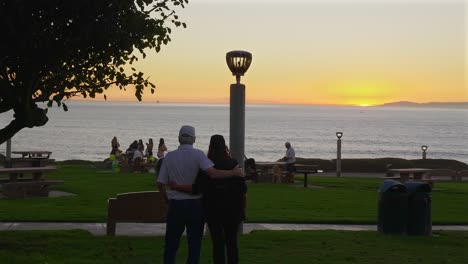 Una-Pareja-Abrazándose-En-Un-Parque-Junto-Al-Océano