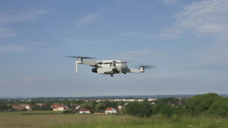 Quadcopter-Consumer-Drohne-Fliegt-An-Sonnigen-Tagen-Langsam-über-Grüne-Vorstadtlandschaft,-Zeitlupe