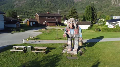 Norwegische-Traditionelle-Trollstatue-Aus-Märchen,-Die-Im-Freien-Bei-Flaa-Hallingdal-Steht---Sommersonnenuntergang-Mit-Langen-Schatten-Und-Häusern-Im-Hintergrund