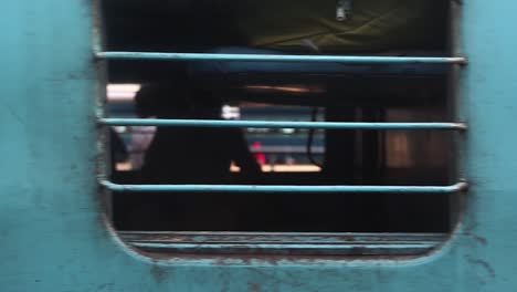 Fahrender-Abfahrender-Zug-Mit-Passagieren,-Die-Aus-Dem-Fenster-In-Die-Kamera-Schauen,-Indien