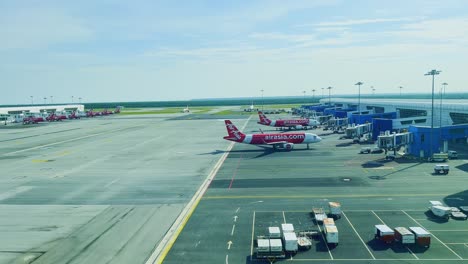 Eine-Seitenwinkelaufnahme-Des-Air-Asia-fluges,-Der-Am-Flughafen-Kuala-Lumpur-Geparkt-Wird