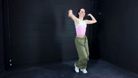 Attraktive-Junge-Tänzerin-Mit-Sportbekleidung,-Die-Sich-Darauf-Vorbereitet,-In-Einem-Studio-Mit-Dunklem-Hintergrund-Zu-Tanzen