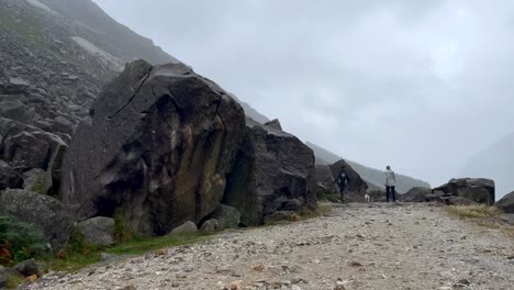 Rückansicht-Von-Wanderern-Mit-Hundetrekking-Auf-Felsigem-Pfad-An-Regnerischen-Tagen-In-Irland---Riesige-Felsen-Und-Steine-Vom-Berg