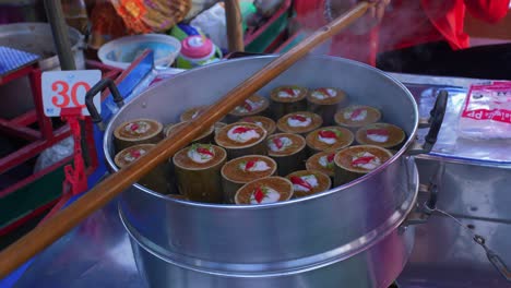 Static-close-up-of-a-pot-of-dim-sum-like-Thai-food-and-a-local-vendor-handing-out-the-packs