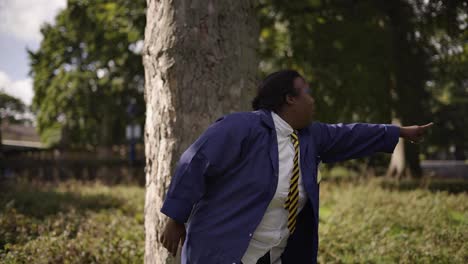 Niña-Negra-Con-Síndrome-De-Down-Señalando-Con-Uniforme-Escolar-Debajo-De-Un-árbol