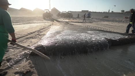 Fishermen-rolling-a-fish-net-on-the-beach-of-Praia-de-Mira-in-Portugal