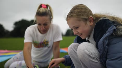 Erwachsene-Und-Kinder-Malen,-Während-Sie-Draußen-In-Einem-Park-Sitzen