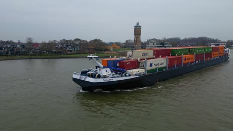 Antenne-Vor-Der-Backbordseite-Des-Scaldis-Containerschiffs,-Das-An-Bewölkten-Tagen-In-Dordrecht-Entlang-Der-Oude-Maas-Fährt