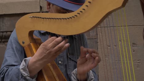 Toma-En-Cámara-Lenta-Del-Hombre-Tocando-El-Arpa-Y-Tocando-En-La-Calle