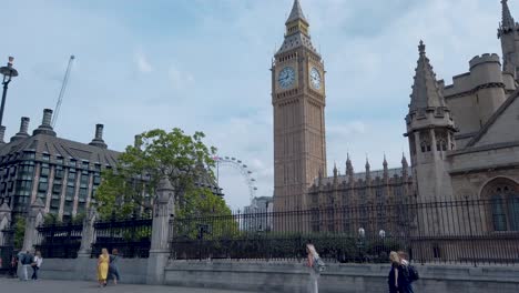 Camina-Al-Lado-Del-Big-Ben-Con-El-Palacio-De-Westminster-Al-Frente-Y-El-London-Eye-Al-Fondo-Y-Gente-Caminando