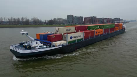 Aerial-Drone-Shot-Off-Port-Side-Of-Scaldis-Container-Ship-Travelling-Along-Oude-Maas-On-Overcast-Day-In-Dordrecht