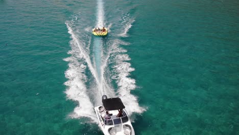 Boot,-Das-Ein-Schlauchboot-Vom-Ufer-In-Der-Nähe-Des-Wasserparks-Am-Strand-Von-Tsambika-In-Griechenland-Schleppt
