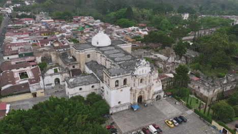 Rotating-aerial-footage-of-the-crumbling-facade-of-a-cathedral-that-slowly-moves-in-over-the-roof-in-Antigua,-Guatemala