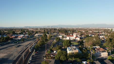 Toma-Aérea-De-Carro-Rápido-Desde-El-Tren-Del-Metro-Pasando-Por-Las-Torres-Watts-Con-El-Centro-De-Los-Ángeles-Al-Fondo