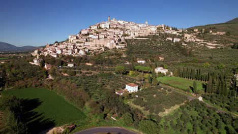 Aerial-rising-shot-of-medieval-town-Trevi-on-top-of-a-green-hill,-Umbria