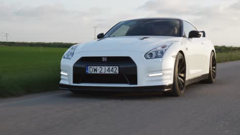 White-Nissan-GTR-sports-car-drive-countryside-road-at-sunset
