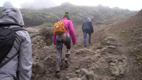 Las-Palmas-de-Gran-Canaria,-Spain---January-24,-2023:-Hiking-group-ascending-to-Roque-Nublo-duroing-a-misty-morning-in-Gran-Canary-Island,-Spain