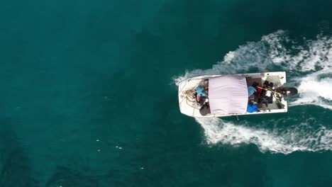 Flat-bottom-boat-on-turquoise-ocean-closeup-rising-from-above-aerial