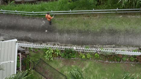 Mahe,-Seychelles-Man-cutting-grass-near-the-road-in-a-village