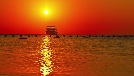 Time-lapse-of-big-boat-floating-on-sea-with-sun-setting-on-top-and-orange-sky