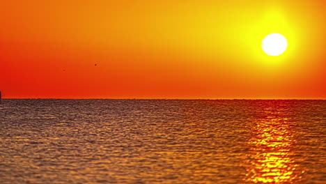 Lebendiger-Bunter-Sonnenuntergang-über-Der-Meeresoberfläche,-Bootssegel-In-Sicht,-Fusionszeitraffer