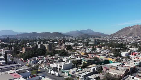Camera-approaches-Saltillo,-Mexico,-a-picturesque-town-hugged-by-dramatic-mountain-ranges-and-clear-blue-skies