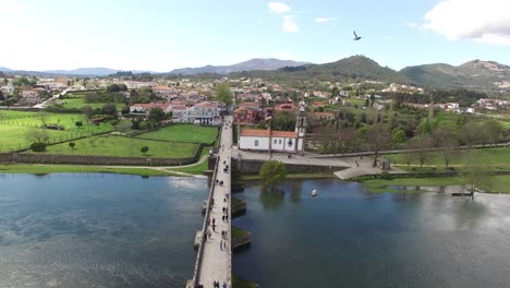 People-walking-in-te-roman-bridge-Aerial-View-City-of-Ponte-de-Lima-and-River-Lima-in-Portugal