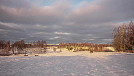Timelapse-of-a-cloudy-sky-over-a-snowy-landscape-with-trees-on-the-background