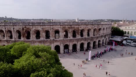 Aerial-view-that-extends-above-the-trees,-to-reveal-the-arenas-of-Nîmes