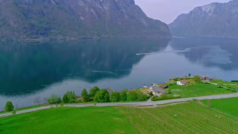 Luftaufnahme-Der-Idyllischen-Küste-Mit-Pfad,-Motorboot-Auf-Fjord-Und-Bergkette-Im-Hintergrund-In-Norwegen