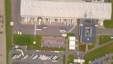 Warehouses,-huge-logistics-center-near-the-highway,-view-of-a-large-number-of-cargo-trailers-and-containers,-international-cargo-transportation,-aerial-view