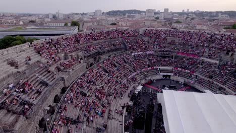 Drone-over-the-Arena-of-Nîmes-at-sunset,-people-are-waiting-for-the-stromae-concert