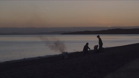 Ein-Blick-Auf-Menschen,-Die-Während-Des-Sonnenuntergangs-Am-Strand-Des-Meeres-Feuer-Machen