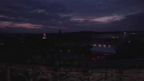 Drone-to-discover-over-the-Arena-of-Nimes-at-sunset,-people-are-waiting-for-the-stromae-concert