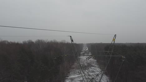 Drone-video-of-going-up-among-power-lines-in-a-snowy-forest