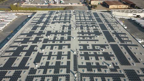 Drohnen-Zeitraffer-Von-Sonnenkollektoren-Auf-Dem-Dach-Eines-Geschäftigen-Distributionszentrums,-Die-Saubere-Energie-Und-Nachhaltigkeit-In-Aktion-Zeigt