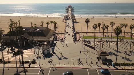 Atemberaubendes-Drohnenvideo-Fängt-Die-Legendäre-Hauptstraße-In-Huntington-Beach,-Kalifornien,-Ein,-Die-In-Den-Pazifischen-Ozean-Führt,-Und-Zeigt-Den-Berühmten-Pier-Und-Die-Lebhafte-Strandatmosphäre