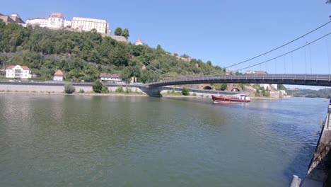 Lastkahn-Segelt-Auf-Der-Donau,-Historische-Festung-Passau-Auf-Hügel--Und-Brückenlandschaft